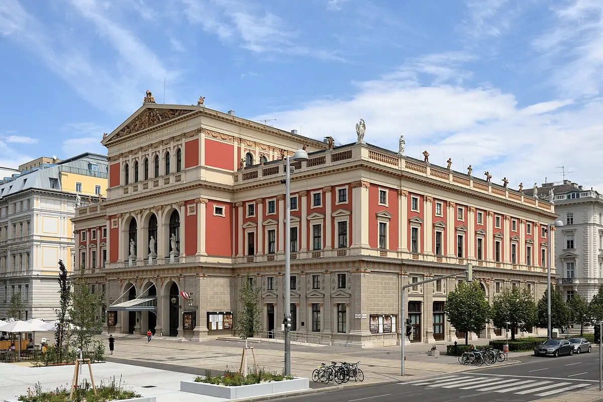 The red and cream facade of the Musikverein in Vienna with its pediment, arched windows and statues along the roofline